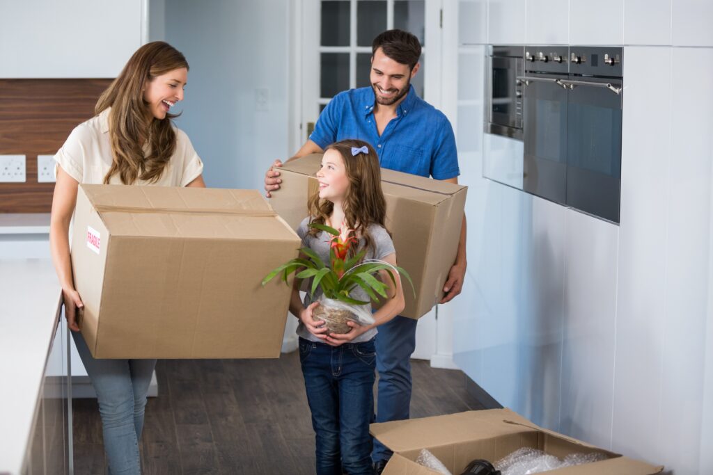 A small family carrying boxes into their new home